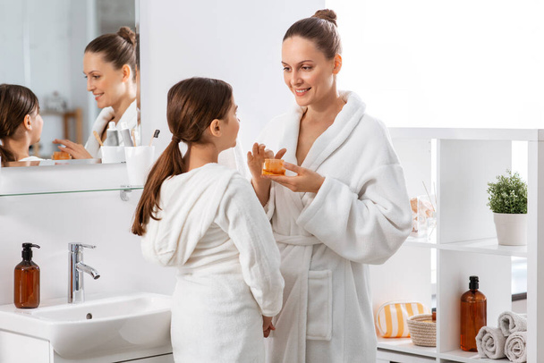 mother and daughter with moisturizer at bathroom - Foto, Bild