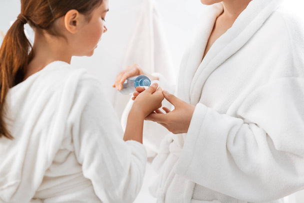 mother and daughter applying lotion to cotton pad - Photo, Image