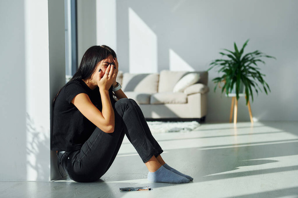 Young woman in casual clothes crying alone at home at daytime. - Foto, Bild