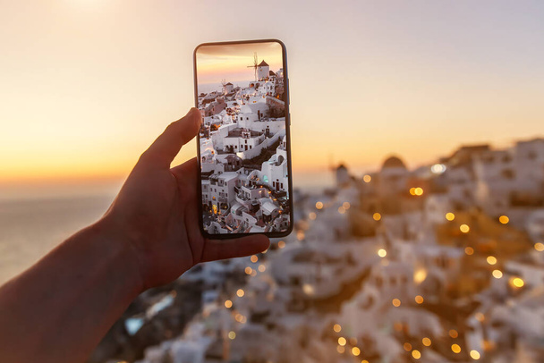 Turista tomando fotos de la famosa vista de Santorini utilizando la cámara del teléfono móvil. Vacaciones en Grecia - Foto, imagen