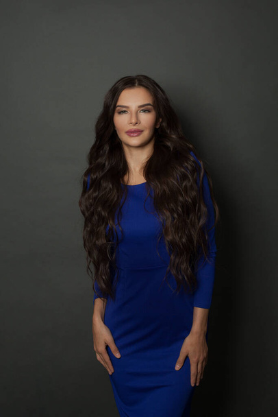 Beauty perfect woman model with long, healthy and shiny wavy hair wearing blue dress. Beautiful female with curly hairstyle . - Photo, Image