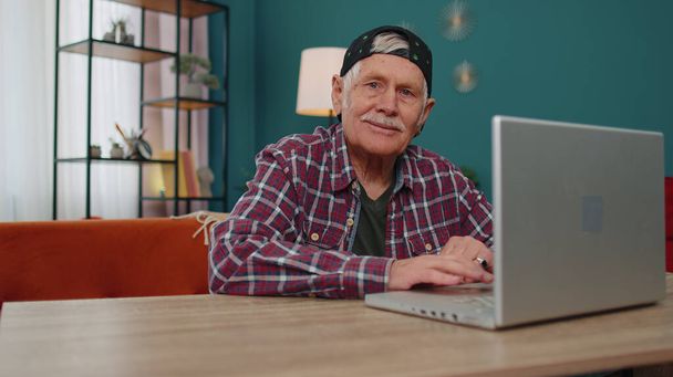 Il nonno anziano inizia a lavorare sul laptop, invia messaggi, fa acquisti online a casa - Foto, immagini