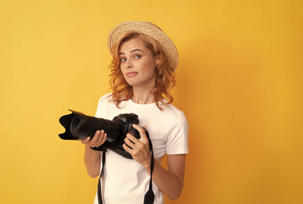 молода руда жінка-фотограф з фотоапаратом у солом'яному капелюсі робить фото, фотосесія
 - Фото, зображення