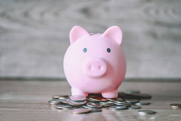 Свинка банка на монетах и деревянном фоне, розовый копилка сбережения денег на обучение или инвестиционная концепция - Фото, изображение
