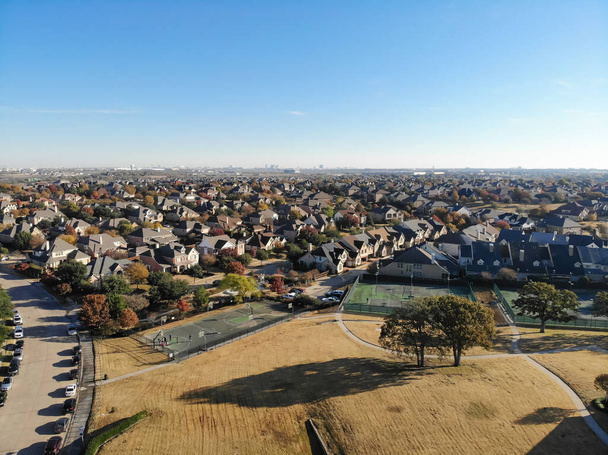 Widok z lotu ptaka duży trawiasty park w pobliżu kompleksu kortów tenisowych w dzielnicy mieszkalnej z kolorowym liści jesieni w pobliżu Dallas, Teksas, Ameryka. Ekskluzywne zaplecze stowarzyszenia właścicieli domów - Zdjęcie, obraz