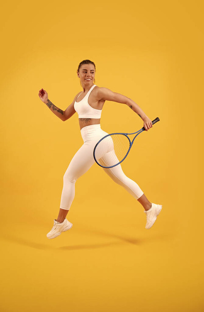 deporte y hobby. actividad de verano. sonriente chica joven en ropa deportiva ejecutar con raqueta. - Foto, imagen