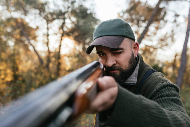 Hunter man aiming his shotgun at camera - Foto, afbeelding