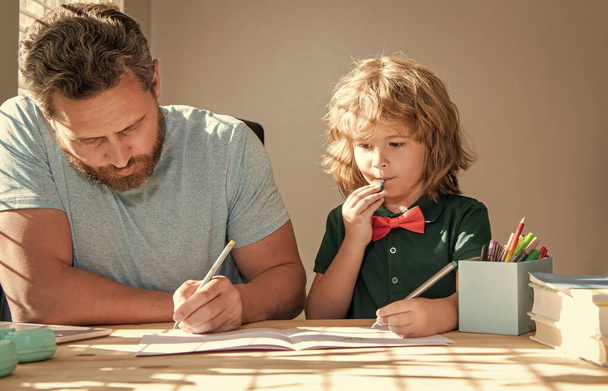 бородатый отец пишет домашнее задание школы со своим сыном в классе, школа - Фото, изображение