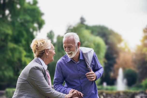 Senior pareja caucásica activa cogida de la mano se ve feliz en el parque por la tarde - Foto, Imagen