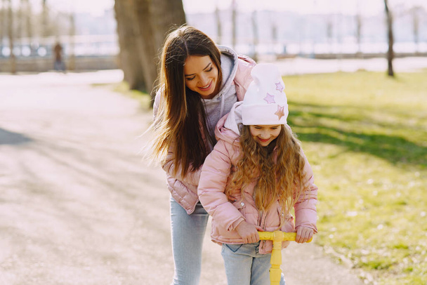 Mother with daughter in a spring park with skate - Foto, Imagen