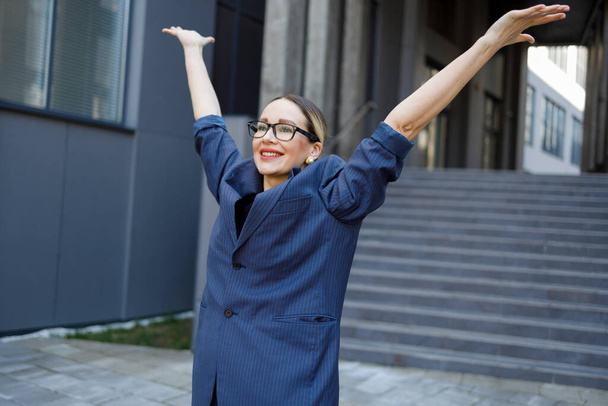 Довольная деловая женщина с поднятыми руками радуется успеху - Фото, изображение