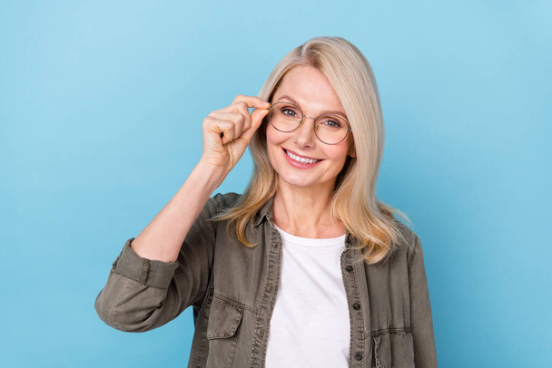 Portrait of positive middle aged lady entrepreneur touch her new optician specs isolated blue pastel color background - Foto, Imagem