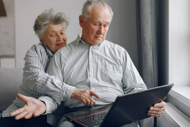 Elegant old couple sitting at home and using a laptop - Foto, Imagen