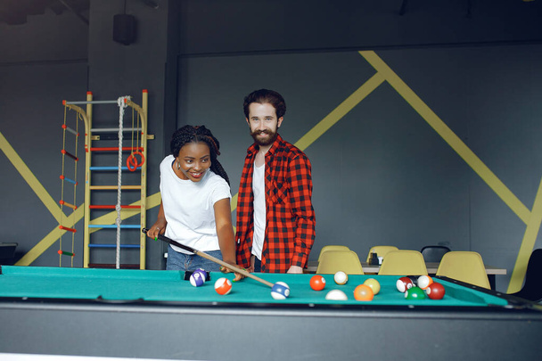 International couple playing a billiard in a club - Фото, зображення