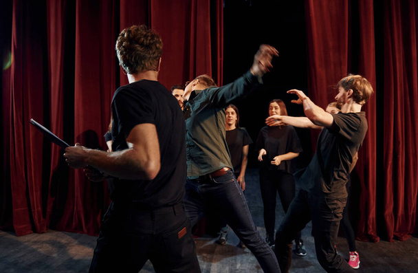 Fight scene. Group of actors in dark colored clothes on rehearsal in the theater. - Foto, Imagen