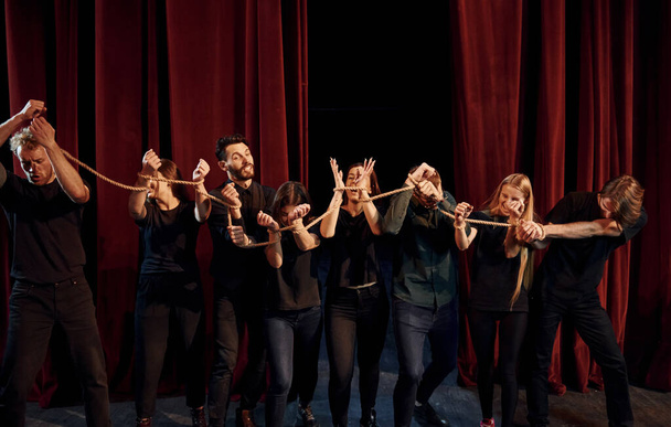 Knot in the hands. Group of actors in dark colored clothes on rehearsal in the theater. - Fotó, kép