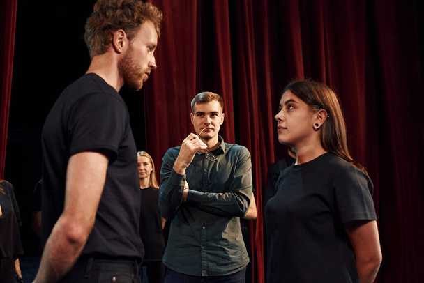 Two people talking. Group of actors in dark colored clothes on rehearsal in the theater. - Foto, Imagen