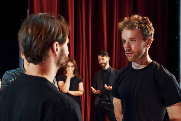 Two people talking. Group of actors in dark colored clothes on rehearsal in the theater. - Fotoğraf, Görsel