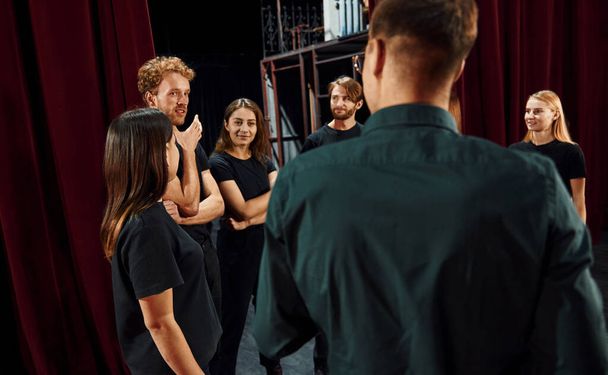 Working together. Group of actors in dark colored clothes on rehearsal in the theater. - Foto, afbeelding