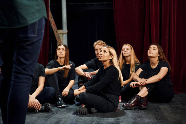 Sitting and listening to man. Group of actors in dark colored clothes on rehearsal in the theater. - Valokuva, kuva