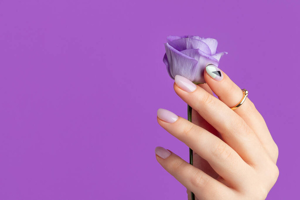 Hermosa mano de las mujeres con el diseño de primavera verano sobre fondo violeta. Manicura, concepto de salón de belleza pedicura - Foto, imagen