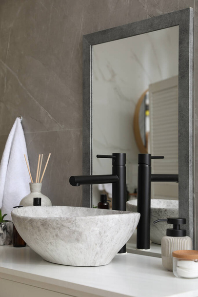 Stone vessel sink with faucet and toiletries on white countertop in bathroom - Foto, Imagem