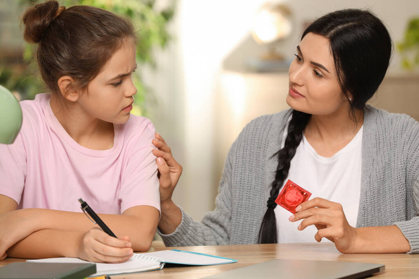 Mutter spricht mit ihrer Teenager-Tochter über Verhütung, während sie zu Hause Hausaufgaben macht. Sexualaufklärungskonzept - Foto, Bild