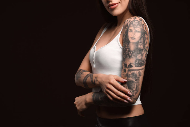 Beautiful woman with tattoos on arms against black background, closeup. Space for text - Foto, Imagem