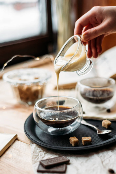 Espresso lasikupissa kaataa maitotiivistettä - ruokosokeri - Valokuva, kuva