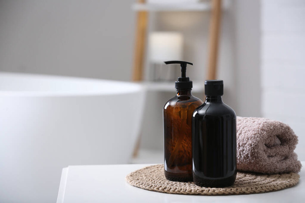 Banyodaki beyaz masada köpük banyosu ve havlu şişeleri, mesaj için yer. - Fotoğraf, Görsel