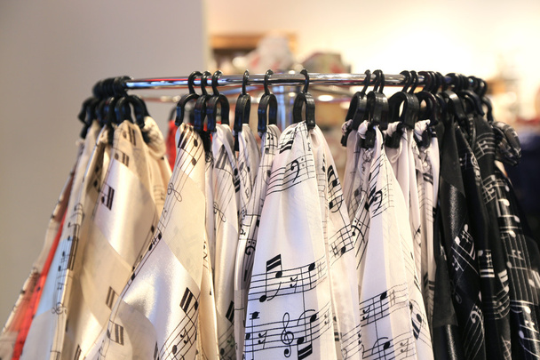 Mantones con notas musicales colgando de ganchos en la tienda
 - Foto, Imagen
