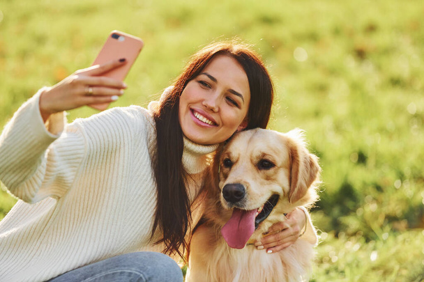 Making selfie. Young woman have a walk with Golden Retriever in the park. - Fotografie, Obrázek