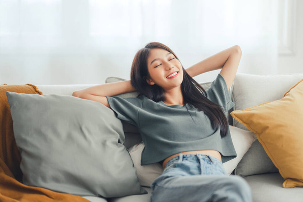 Крупним планом - розслаблена молода азіатка насолоджується відпочинком на зручному дивані вдома, спокійна приваблива дівчина розслабляється і дихає свіжим повітрям вдома, копіює простір
. - Фото, зображення