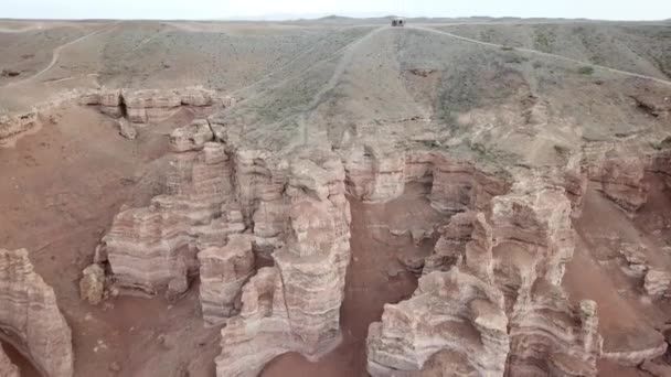 Grand canyon Charyn. Rocce da rocce sedimentarie. Enormi crepe nelle rocce. Il terreno è rosso-arancio. Vista dall'alto da un drone. C'è una strada nel centro. Strati di terra in diversi colori. - Filmati, video