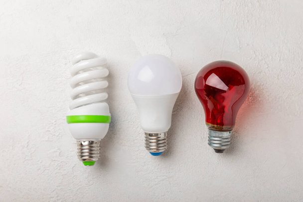 電球がついてる。エネルギー効率の概念です。LEDランプ対白熱灯。灰色のセメントの背景に組成。経済的で環境に優しい電球の概念を使用する. - 写真・画像