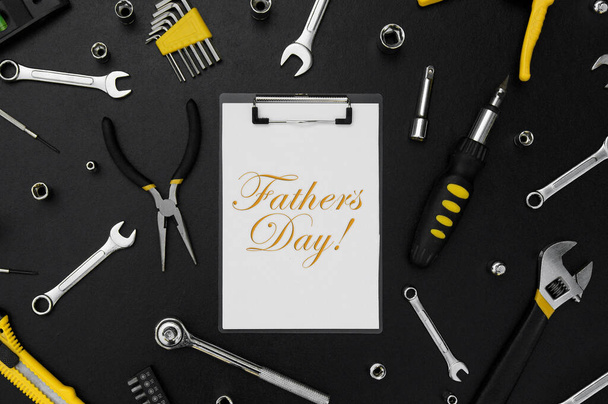 Litery Happy Father 's Day z wieloma różnymi narzędziami do naprawy na czarnym stole. Koncepcja Dnia Ojca. - Zdjęcie, obraz