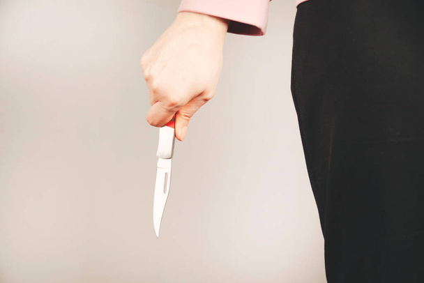 woman hand holding knife in back on gray background - Foto, Imagem
