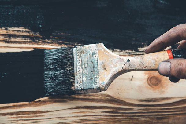man hand black paint and brush on wood - Фото, изображение