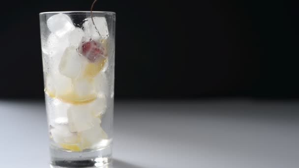 verter limonada en un vaso con hielo y frutas sobre un fondo blanco y negro - Metraje, vídeo