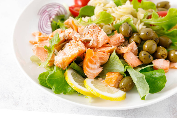 Grilled salmon salad with fresh lettuce, tomatoes, green olives, red onion and pasta. Healthy food, diet - Photo, image