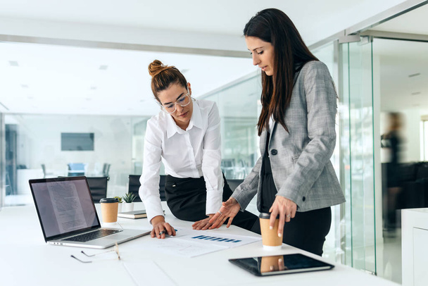 Shot of successful business women standing around computer for presentation of work in a modern startup. - Фото, зображення