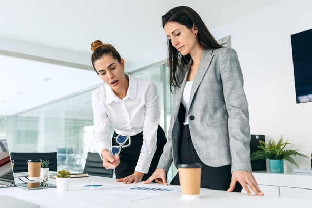 Shot of successful business women standing around computer for presentation of work in a modern startup. - Фото, зображення