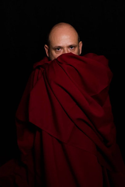 Человек, покрытый красной тканью на черном фоне. Сальвадор, Бахия, Бразилия. - Фото, изображение