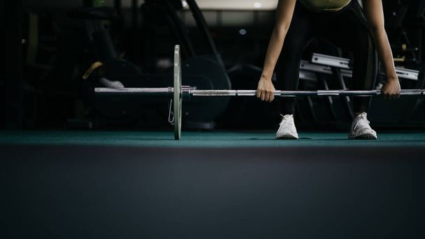 A woman is working out in a fitness center, lifting steel numbells to build muscles in her arms and shoulders. Fitness concepts for health and wellness lifestyles, build muscles of the body. - Photo, Image