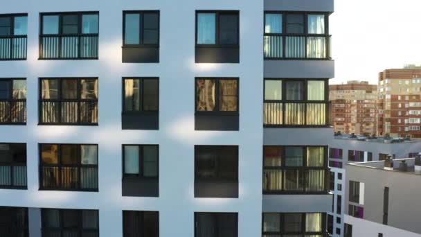 Beyaz çok katlı binanın karanlık pencereleri. Stok görüntüleri. Güneşli bir yaz gününde bir apartman dairesinin gökdelenlerinin havadan görünüşü. - Video, Çekim