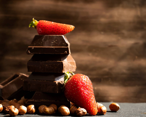 Dark chocolate, fresh strawberries, nuts on a dark background - Foto, Bild
