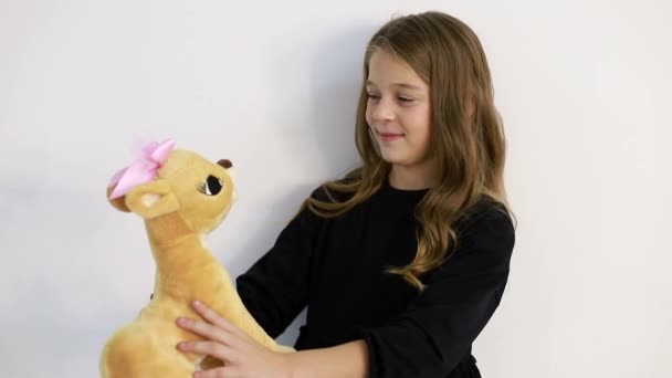 A child with a soft toy on a white background, she tenderly hugs the toy. - Footage, Video