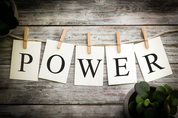 A set of printed cards spelling the word POWER on an aged wooden background. - Photo, Image