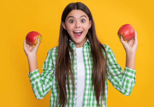 amazed teen child with apple on yellow background - Foto, Imagen