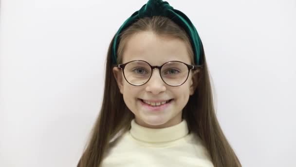 Uśmiechnięta dziewczynka w okularach odizolowana na białym tle - Materiał filmowy, wideo